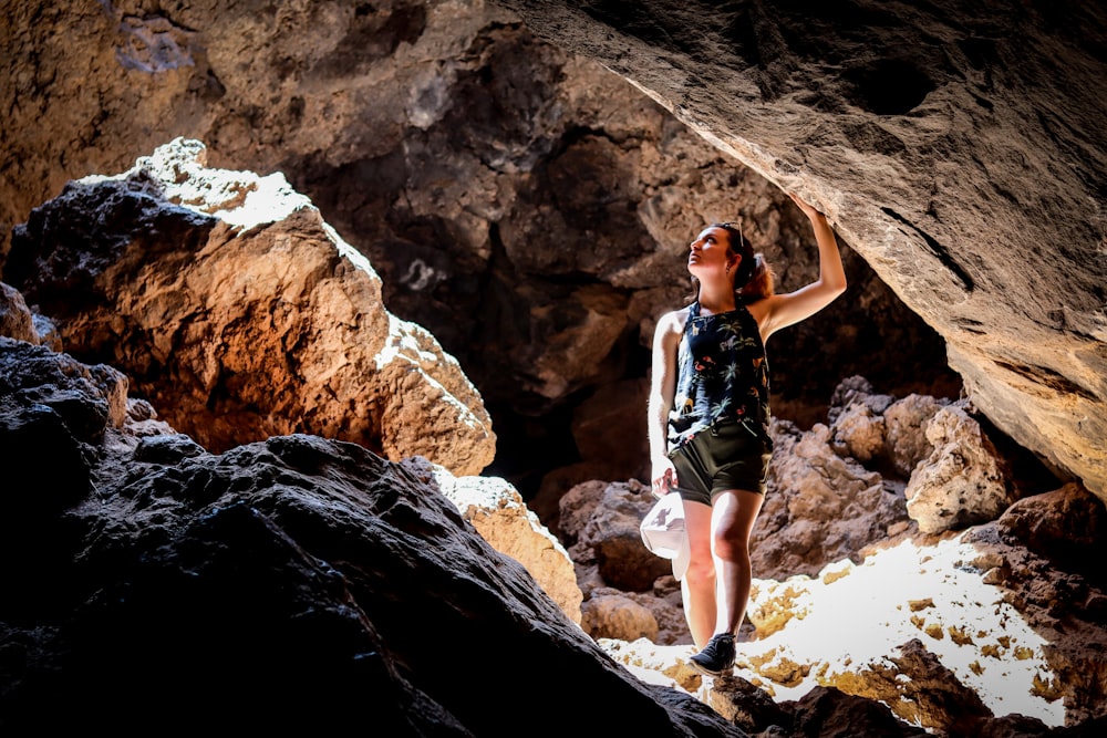 woman in black tank top and white shorts standing on rocky mountain during daytime