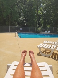 A sparkling blue swimming pool with stone edges and lounge chairs under the sun.