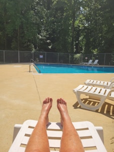A sparkling blue swimming pool in a sunny backyard with lounge chairs.