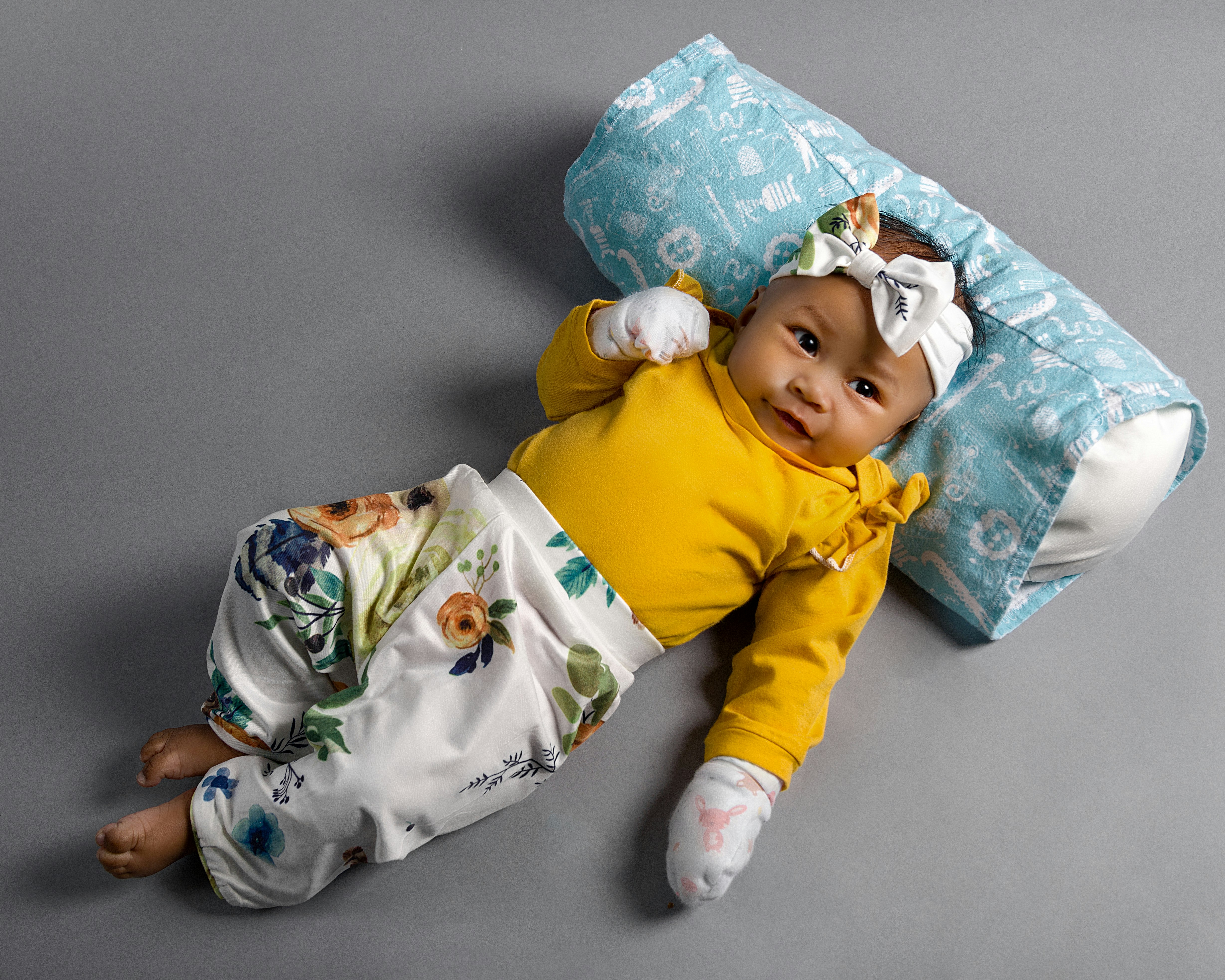baby in yellow sweater lying on white and green textile