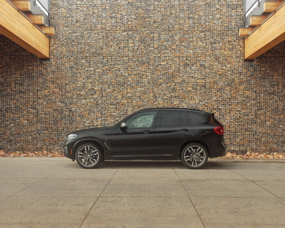 black sedan parked beside brown brick wall