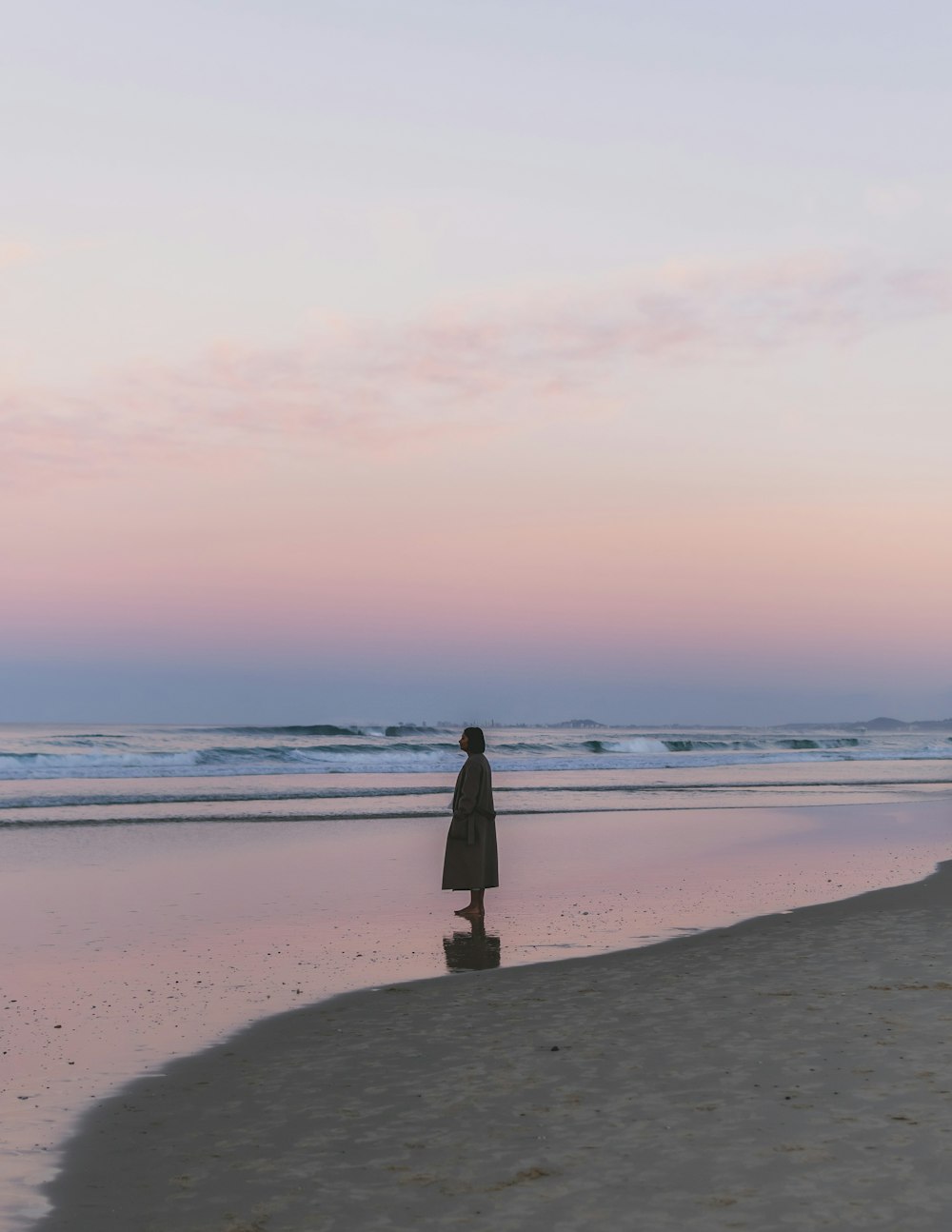 Frau in schwarzem Kleid tagsüber am Strand stehend
