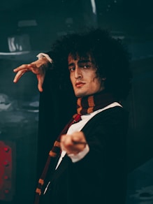 man in black suit jacket raising his right hand