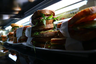 Stack of golden breaded milanesa sandwiches with lettuce and tomato, ready to eat.