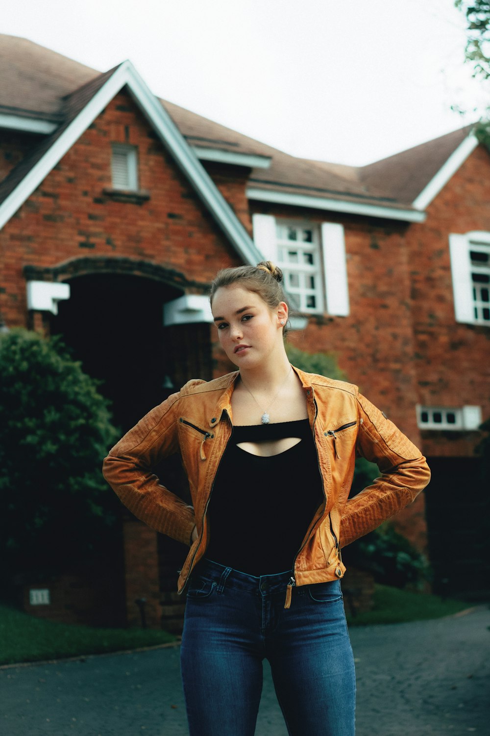 a woman standing in front of a red brick house