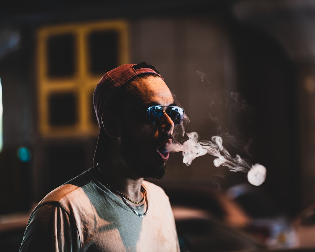 Un homme dans la rue, fumant une cigarette électronique en faisant des ronds de fumée