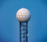 A sleek radar installation scanning a clear blue sky at dawn.