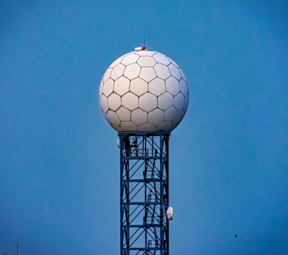 A sleek radar installation scanning a clear blue sky at dawn.