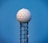 A tall radar tower features a spherical dome with a hexagonal pattern sitting atop a lattice metal structure against a clear blue sky.