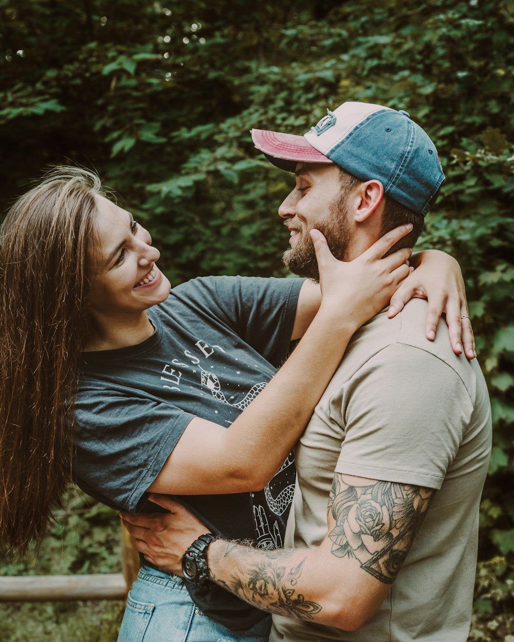 man in gray crew neck t-shirt kissing woman in blue denim cap