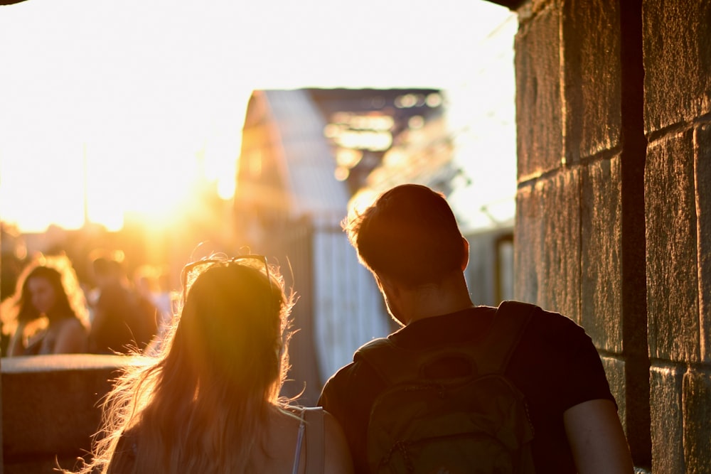 man and woman standing beside brown concrete wall during daytime