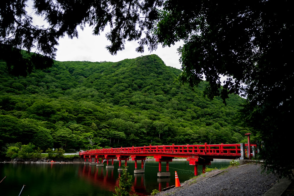 red bridge over river near green mountain during daytime