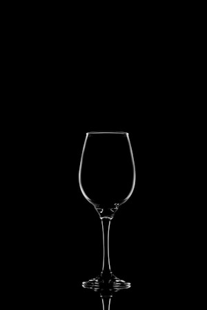 A single wine glass with a transparent outline against a black background, creating a minimalist and sleek silhouette.