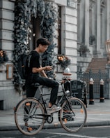 man in black t-shirt and black cap riding on black city bicycle