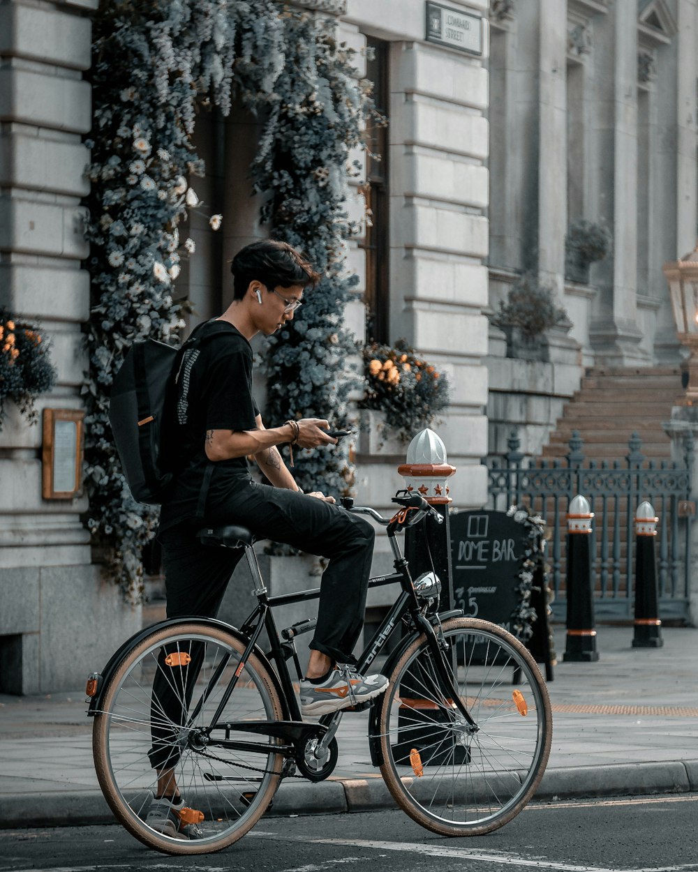 Hombre con camiseta negra y gorra negra montando en bicicleta negra de la ciudad