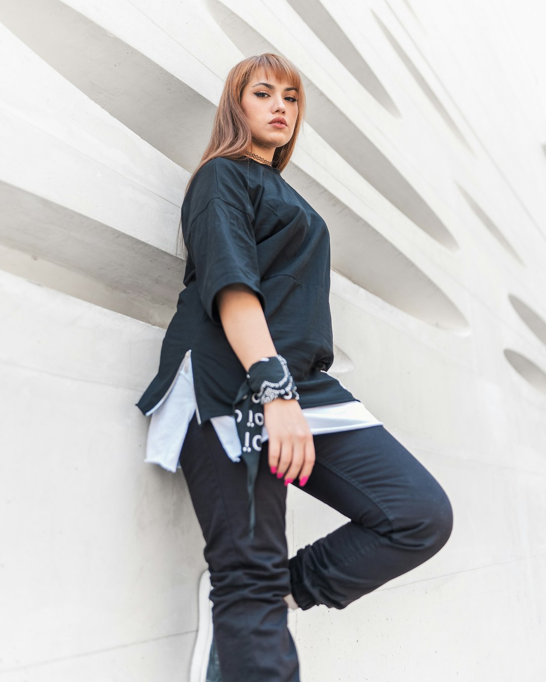 woman in black shirt and blue denim jeans sitting on white concrete wall