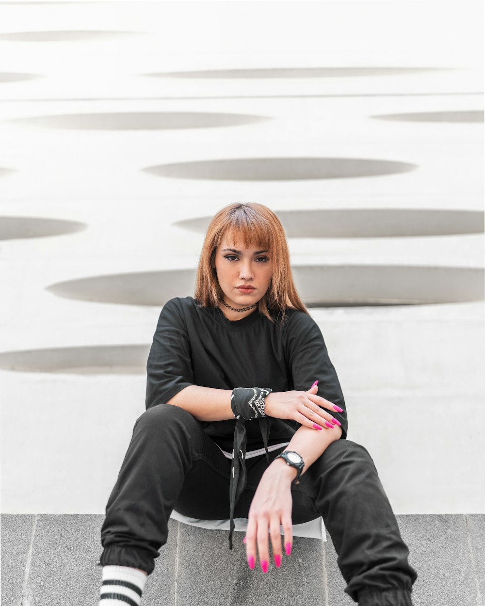 Femme en chemise noire à manches longues assise sur des escaliers en béton gris