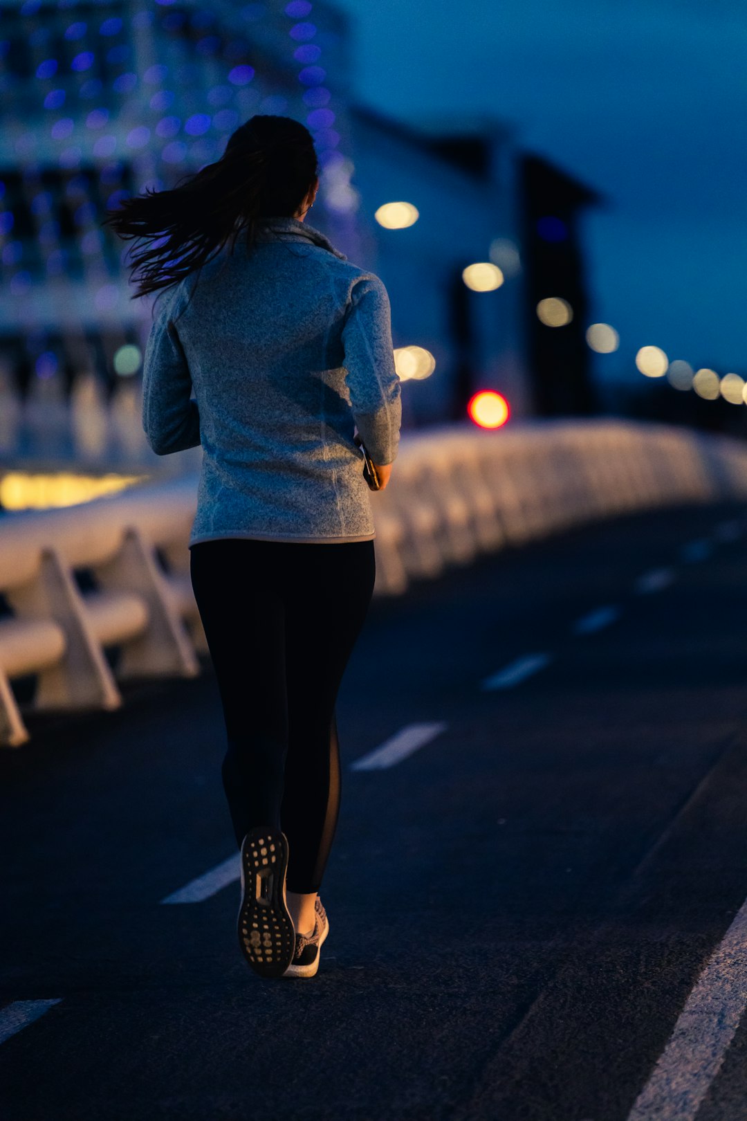 woman in blue long sleeve shirt and black pants standing on sidewalk during night time