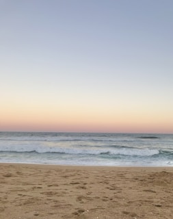 A peaceful beach scene with gentle waves under a pastel sunset sky.