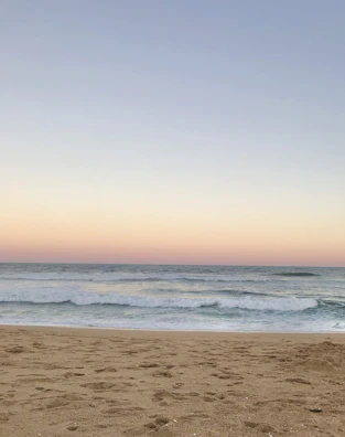 A peaceful beach scene with gentle waves rolling in under a pastel sunset sky.