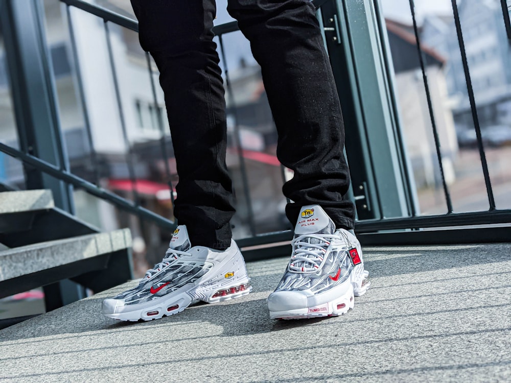 person in black pants and white and red nike sneakers