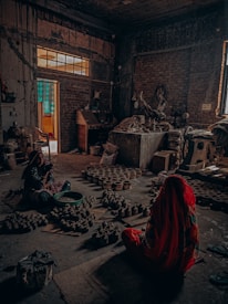woman in red dress sitting on floor near brown brick building during daytime