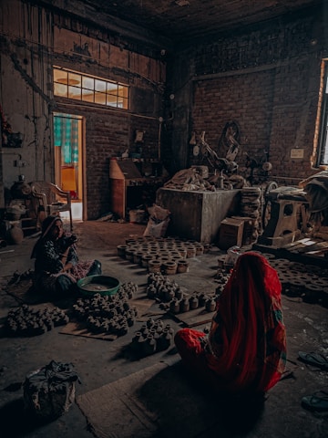 woman in red dress sitting on floor near brown brick building during daytime