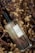 A perfume bottle labeled 'Gift of Plant Eau de Parfum Sunit Ricefield' is placed among dried flowers and plants, creating a rustic and natural setting. The bottle is made of clear glass with a black cap, and the label is simple and elegant.