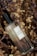 A perfume bottle labeled 'Gift of Plant Eau de Parfum Sunit Ricefield' is placed among dried flowers and plants, creating a rustic and natural setting. The bottle is made of clear glass with a black cap, and the label is simple and elegant.