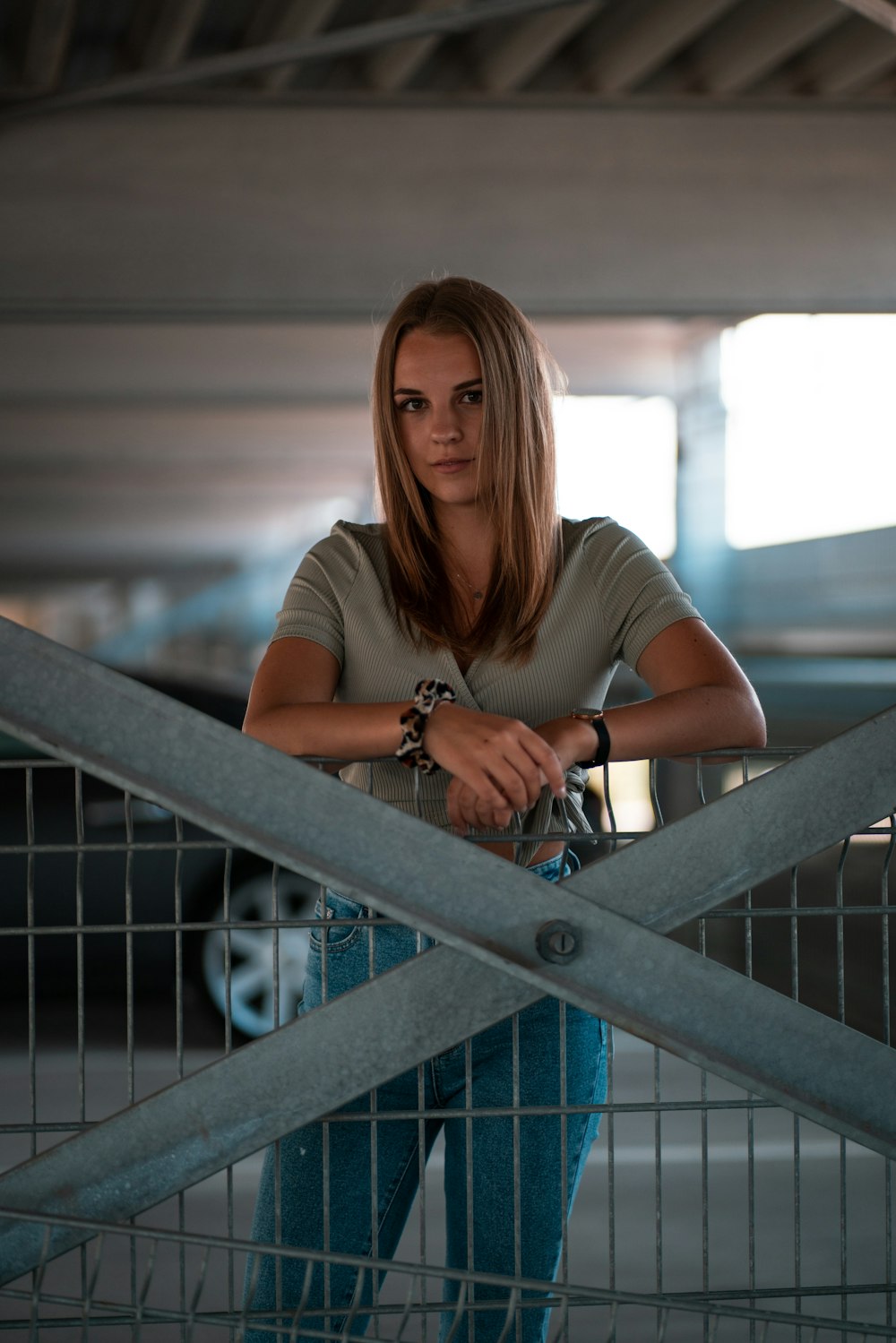 woman in white t-shirt and blue denim jeans sitting on gray metal railings
