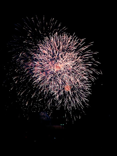 A vibrant display of Ayyan 120 shots fireworks bursting in the night sky with multi-colored sparks.