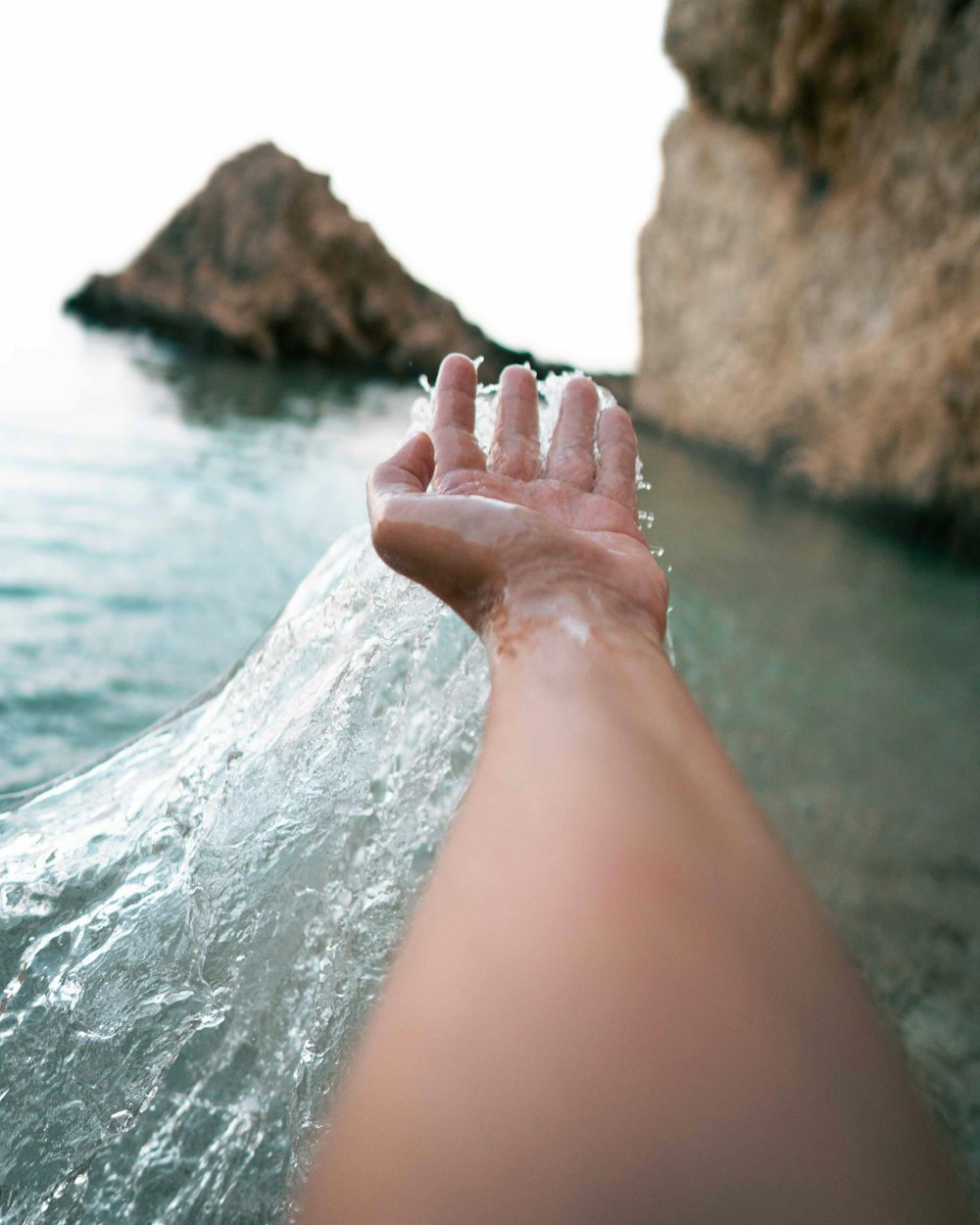 persons feet on brown rock near body of water during daytime