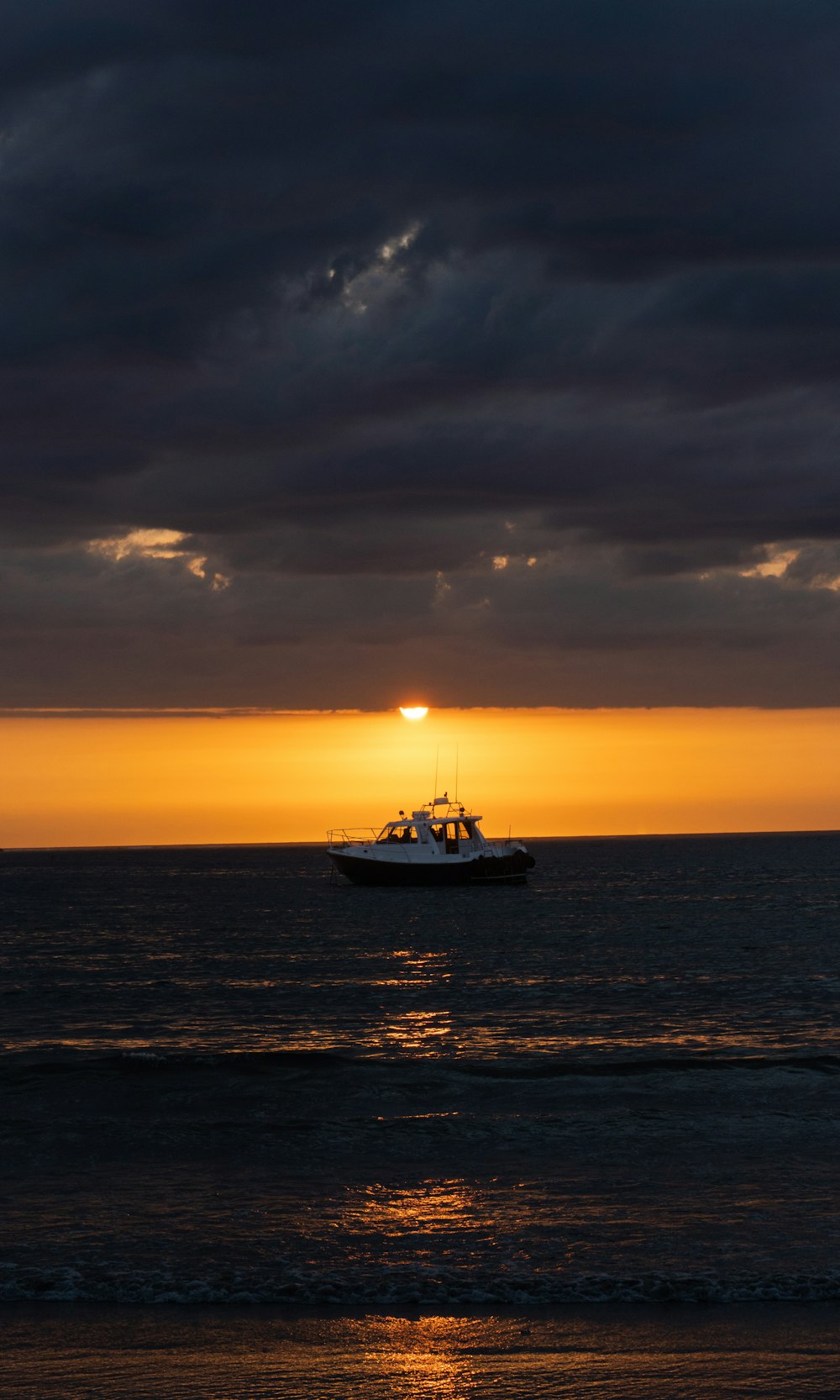 white and black boat on sea during sunset