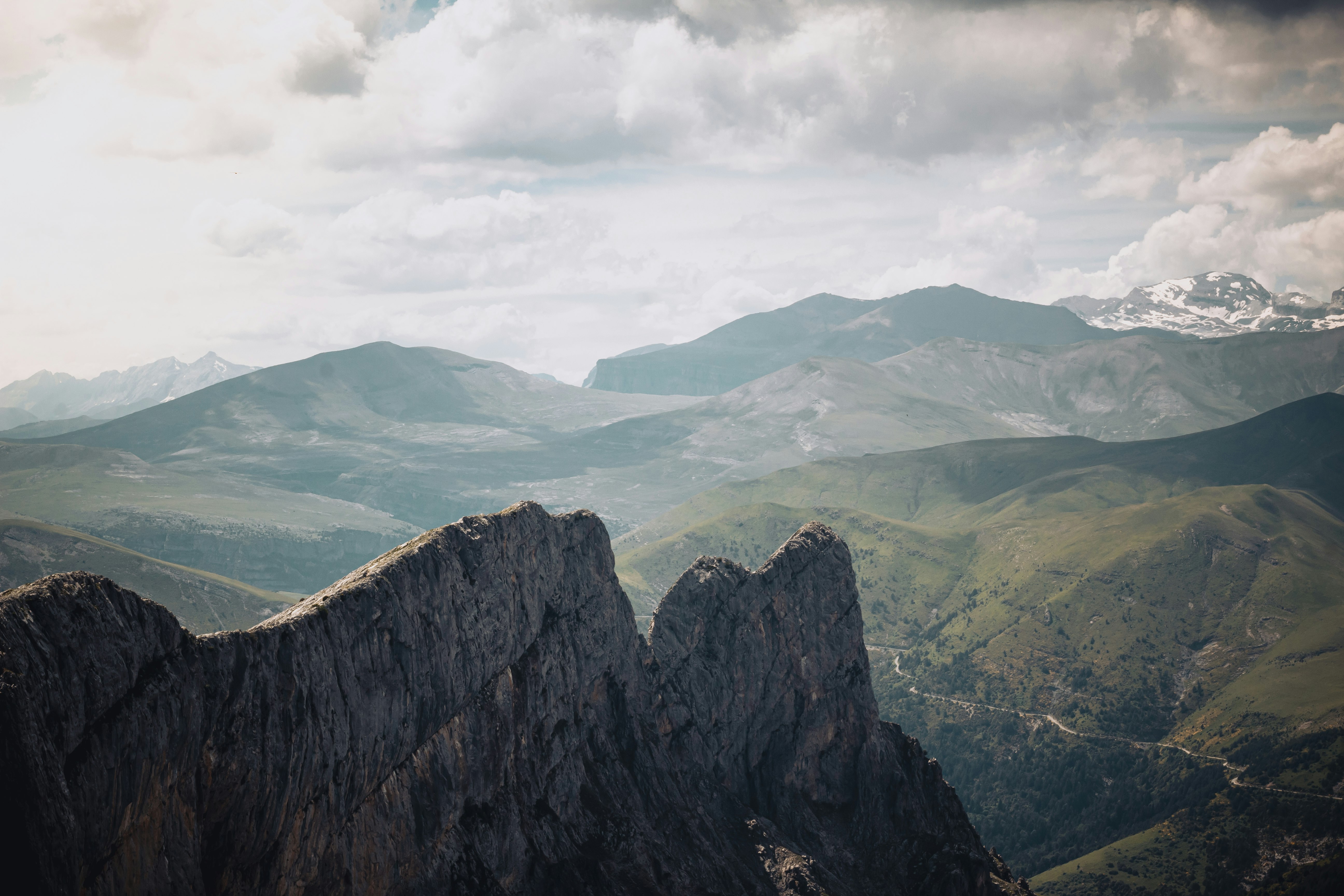 black and gray rock formation near green grass field under white clouds during daytime