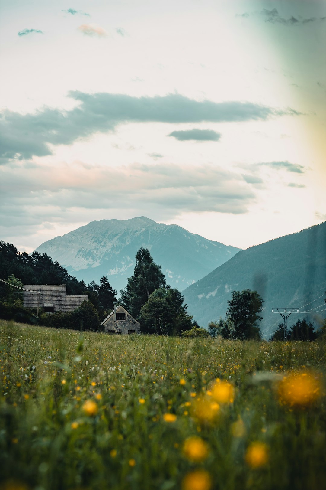 green grass field near mountain under white clouds during daytime