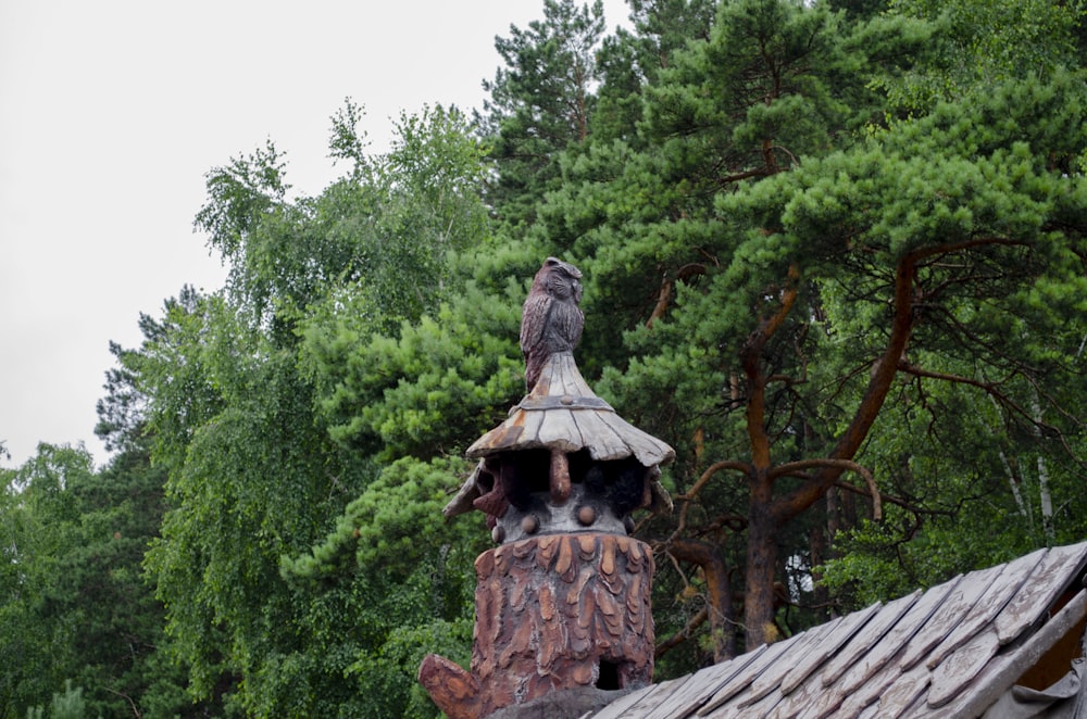 brown wooden statue near green trees during daytime