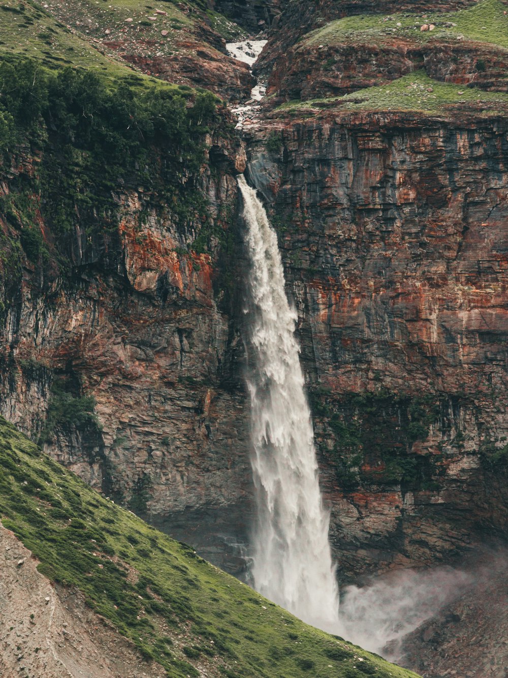 Chutes d’eau sur la montagne rocheuse brune pendant la journée