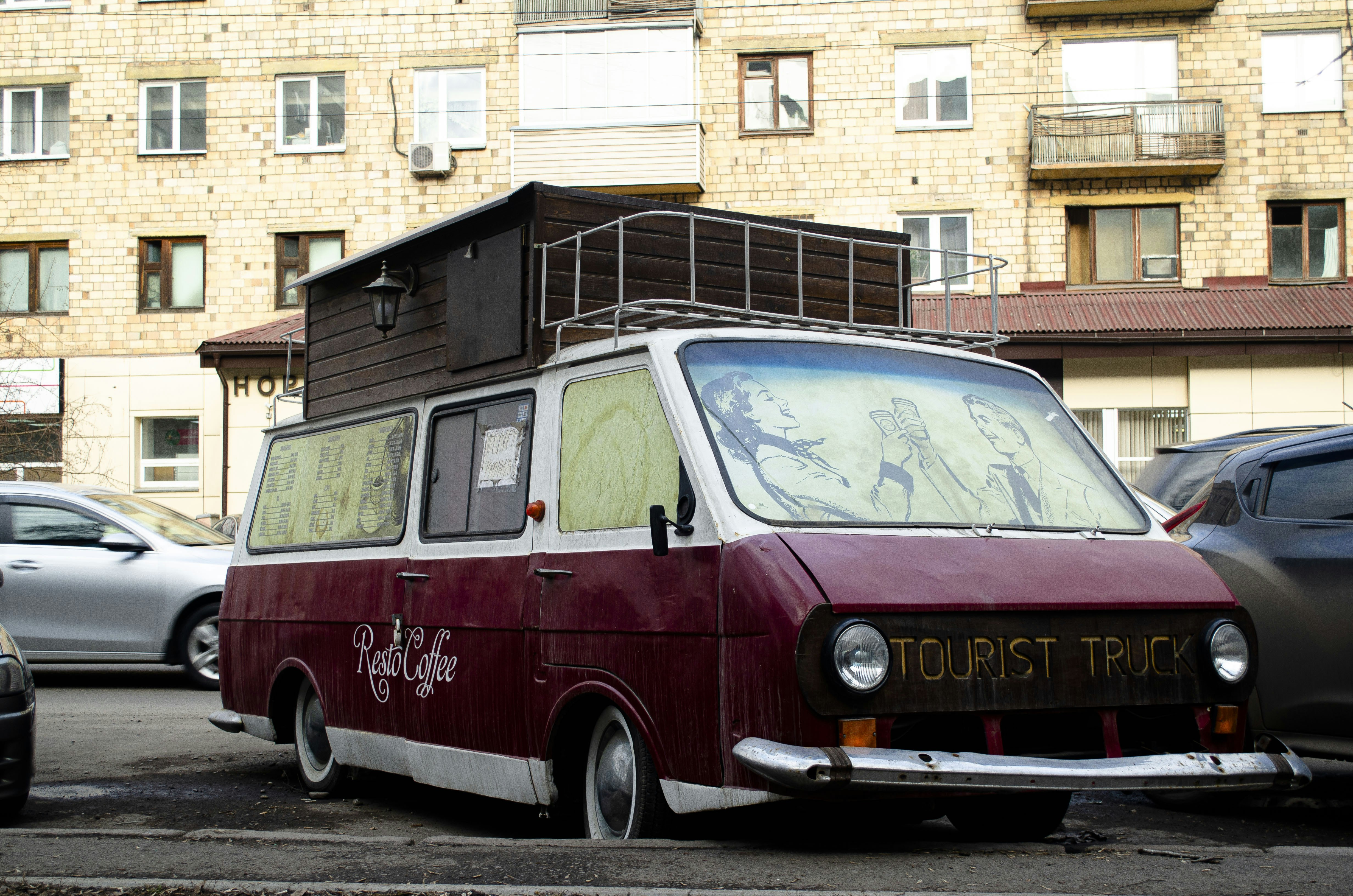red and white volkswagen t-2 van parked beside brown building during daytime