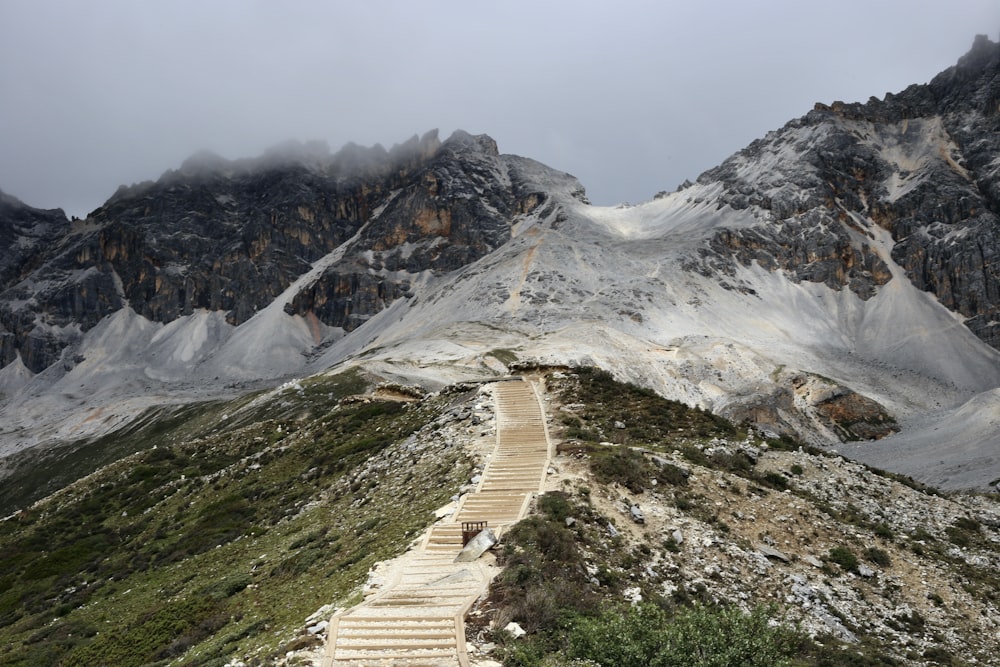 brown wooden pathway on mountain covered with snow