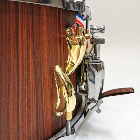 Close-up of an antique snare drum with intricate metalwork, resting on a velvet cloth.