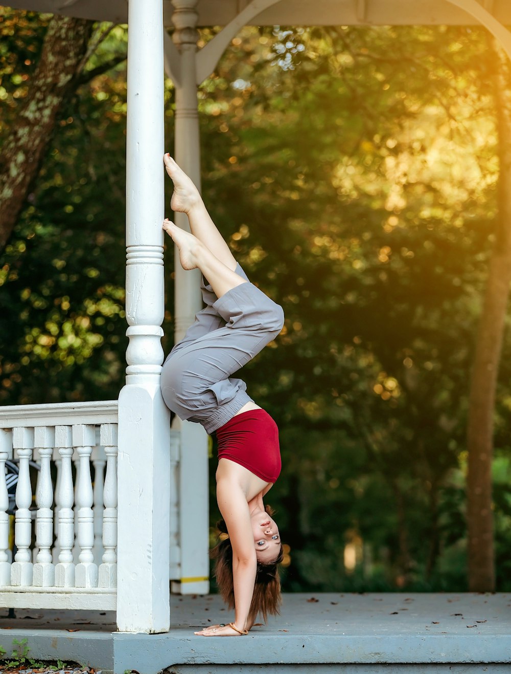 woman in red tank top and gray pants climbing on white wooden fence during daytime