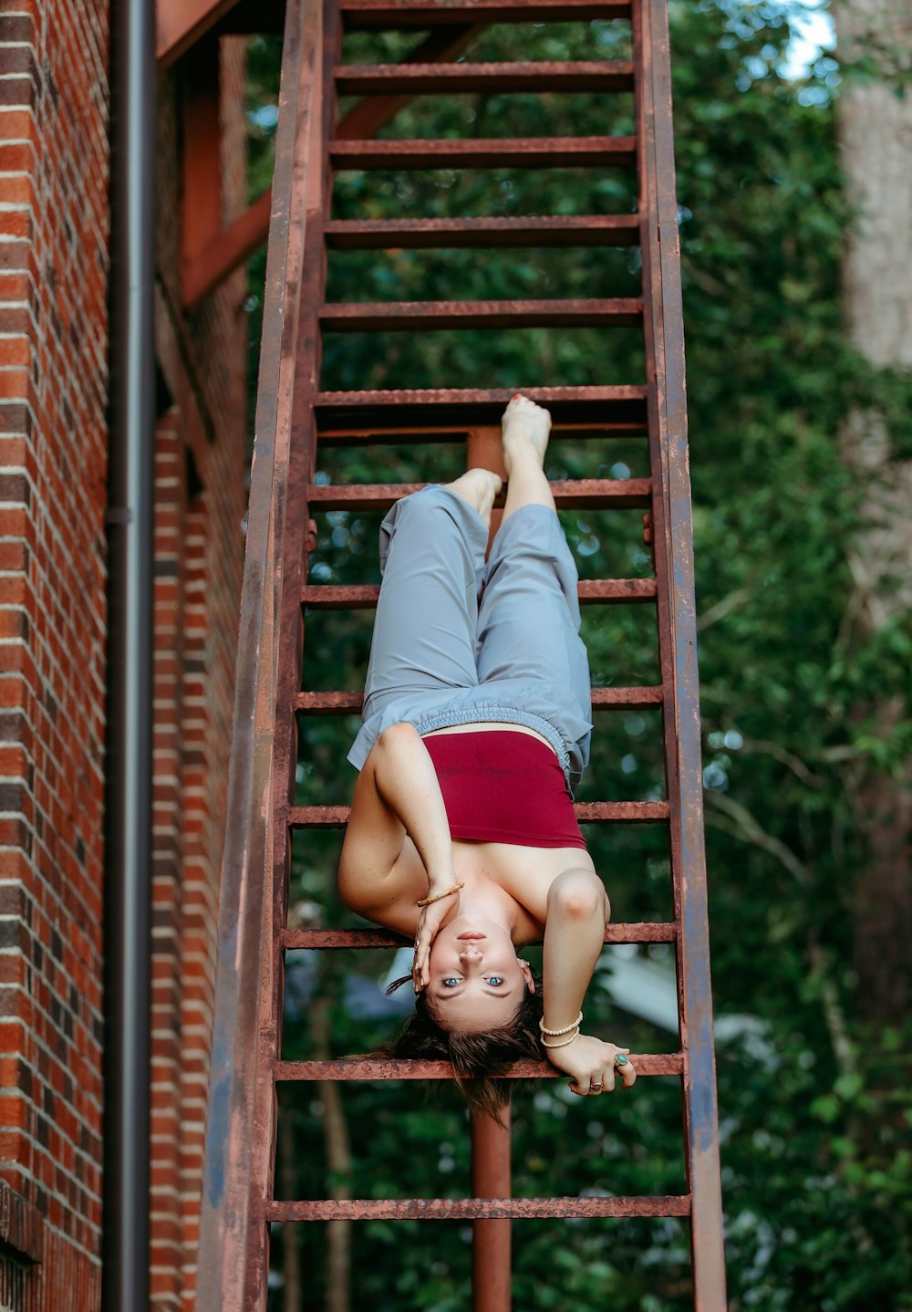 girl in blue and white long sleeve shirt and red skirt lying on brown wooden stairs