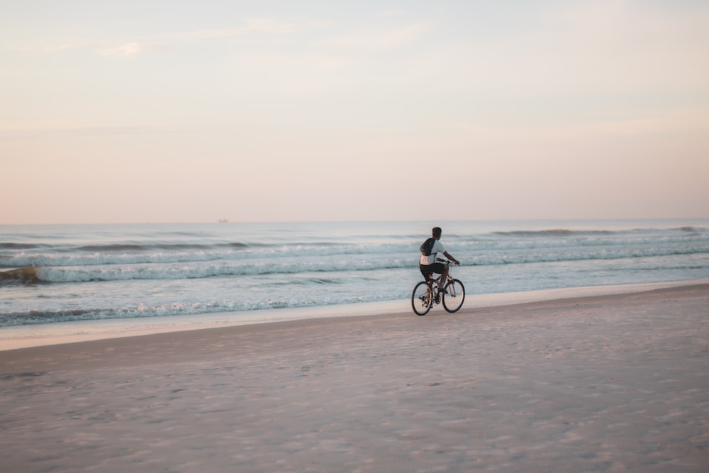 man in black shirt riding bicycle on beach during daytime