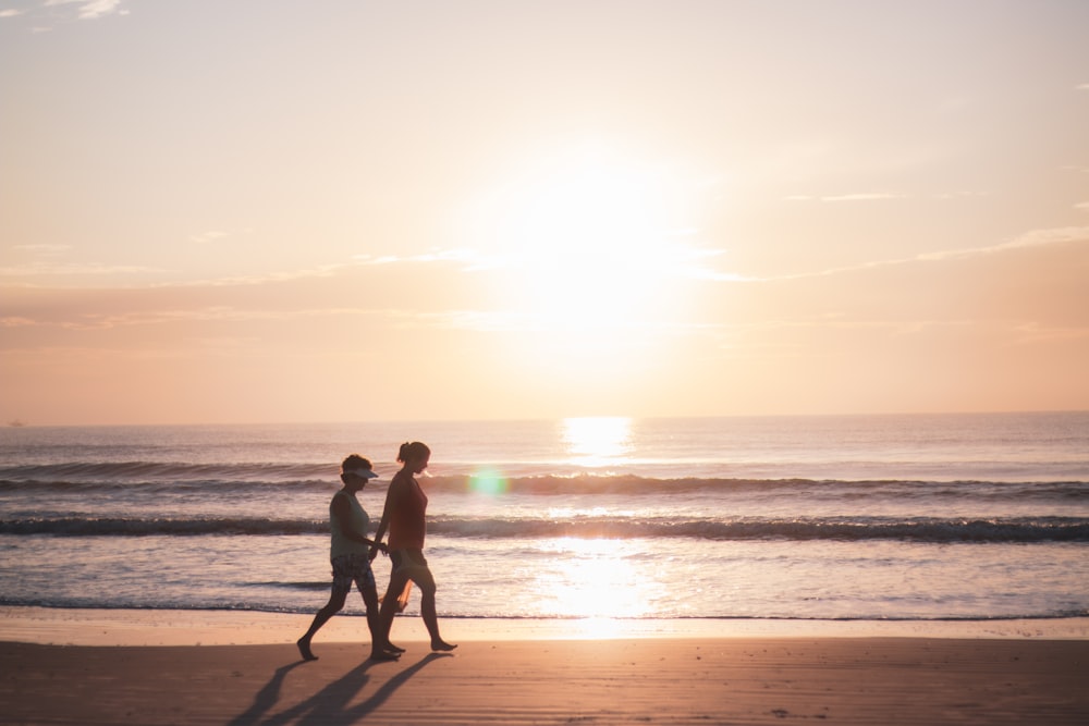 2 men standing on beach during sunset