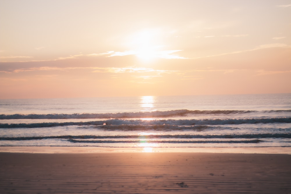 sea waves crashing on shore during sunset