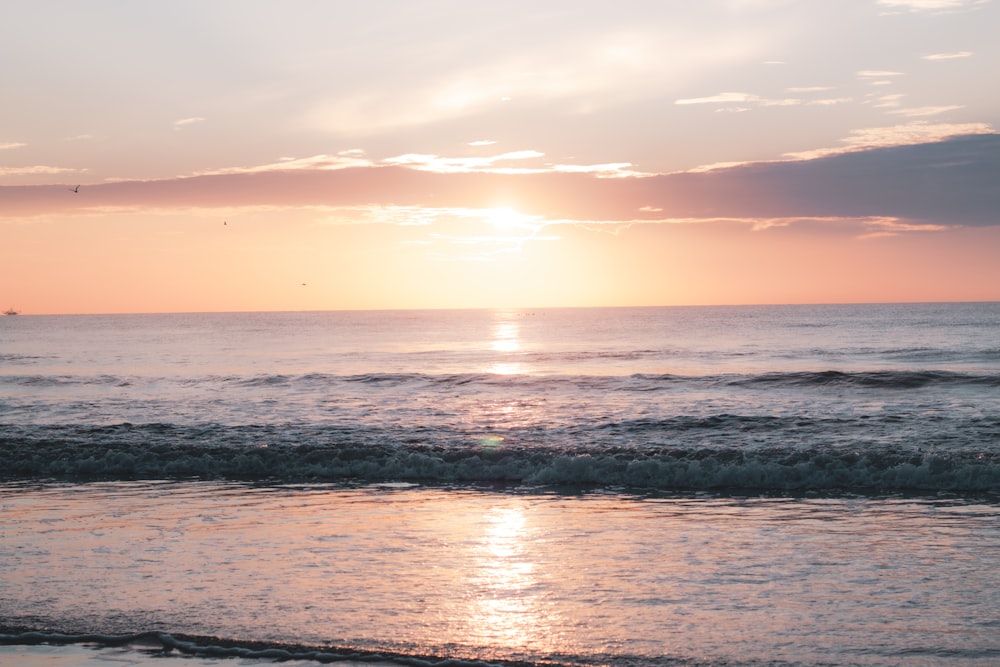 sea waves crashing on shore during sunset