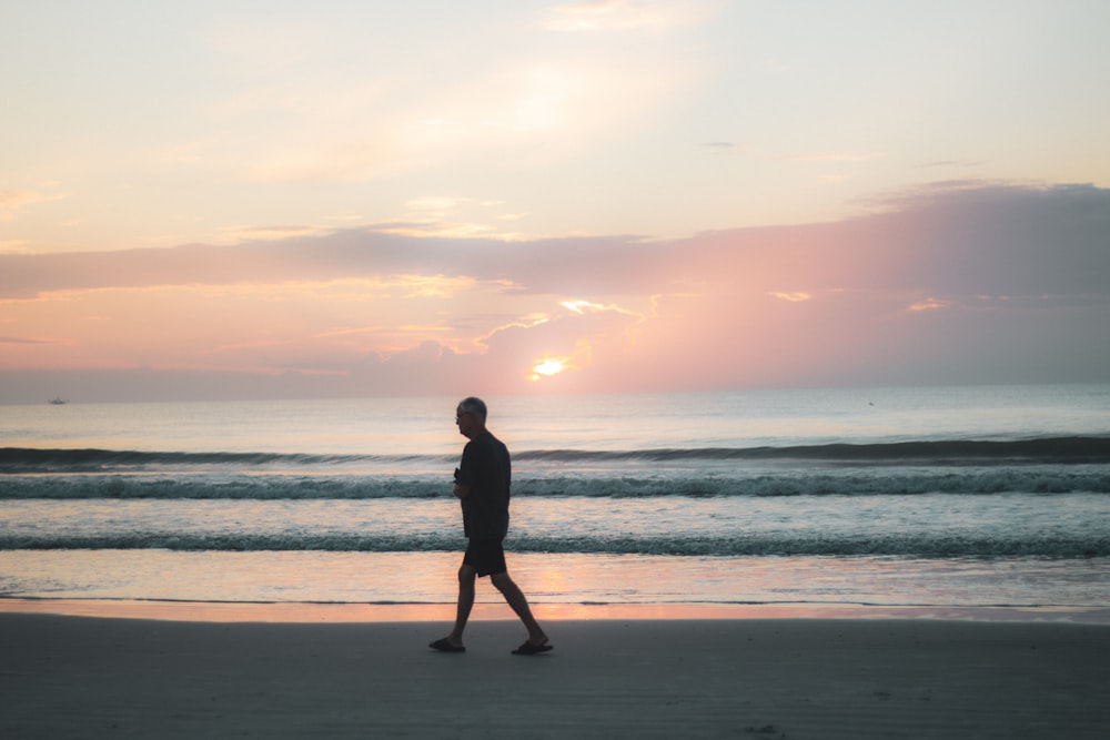 silhouette of man standing on beach during sunset