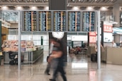 A busy airport terminal with travelers and flight information screens.