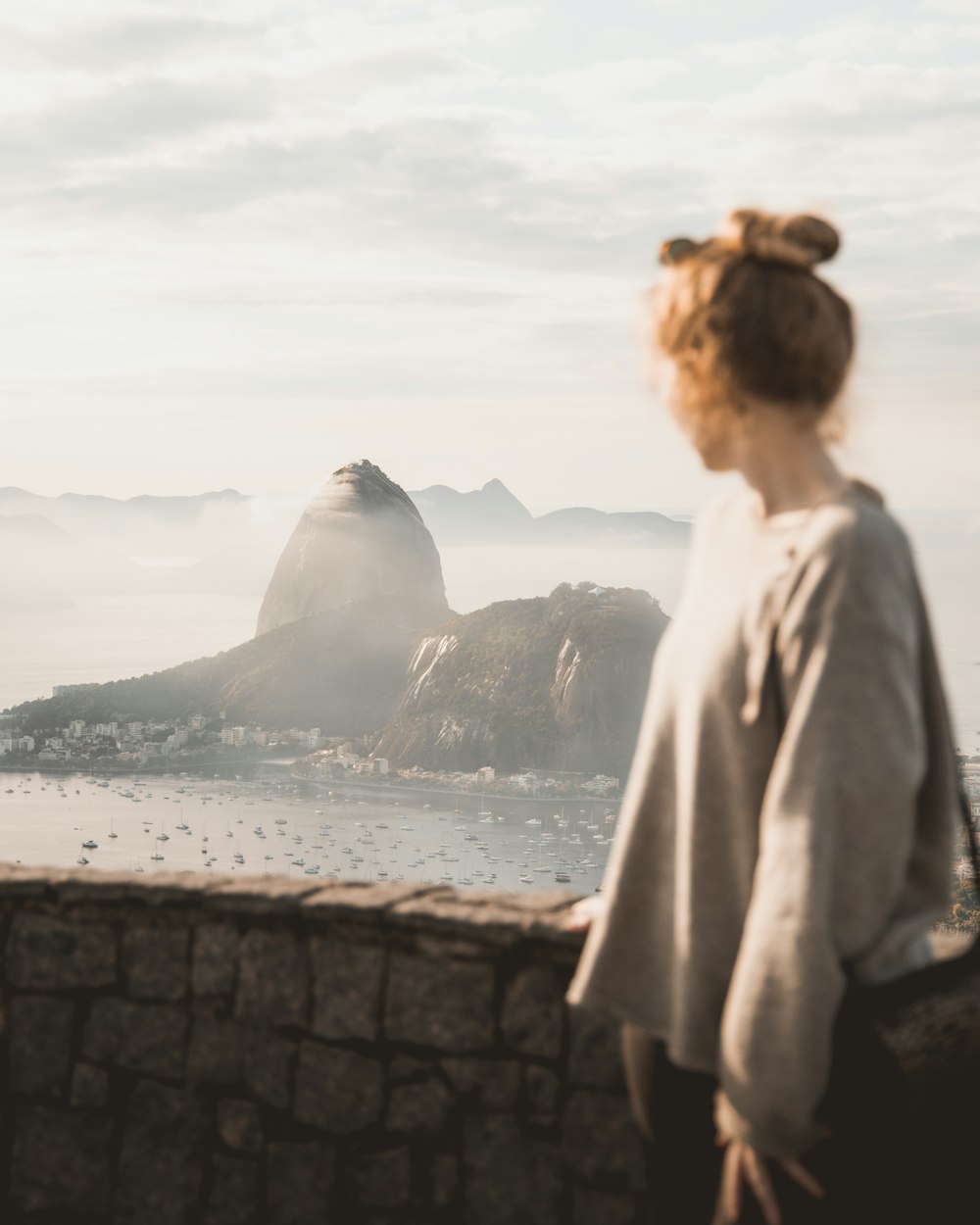 woman in white coat standing on rock formation near body of water during daytime