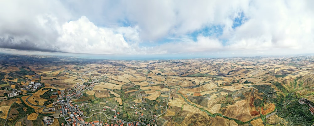 vista aerea del campo verde e marrone sotto il cielo nuvoloso durante il giorno